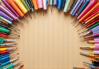 Illustrative image showing a variety of craft tools like brushes, scissors, thread, and colorful paper on a workbench